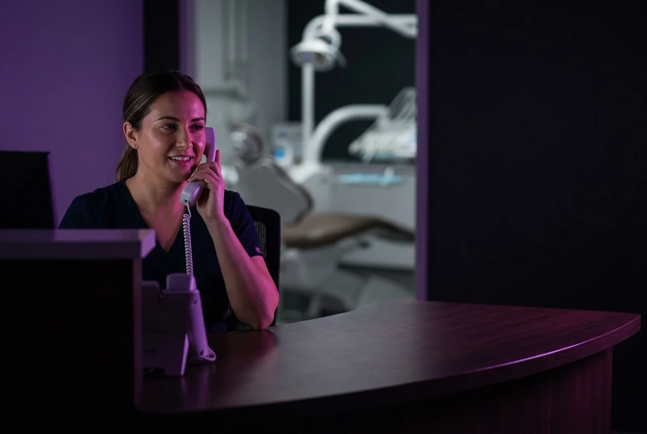 Assistente risponde al telefono alla reception di uno studio dentistico