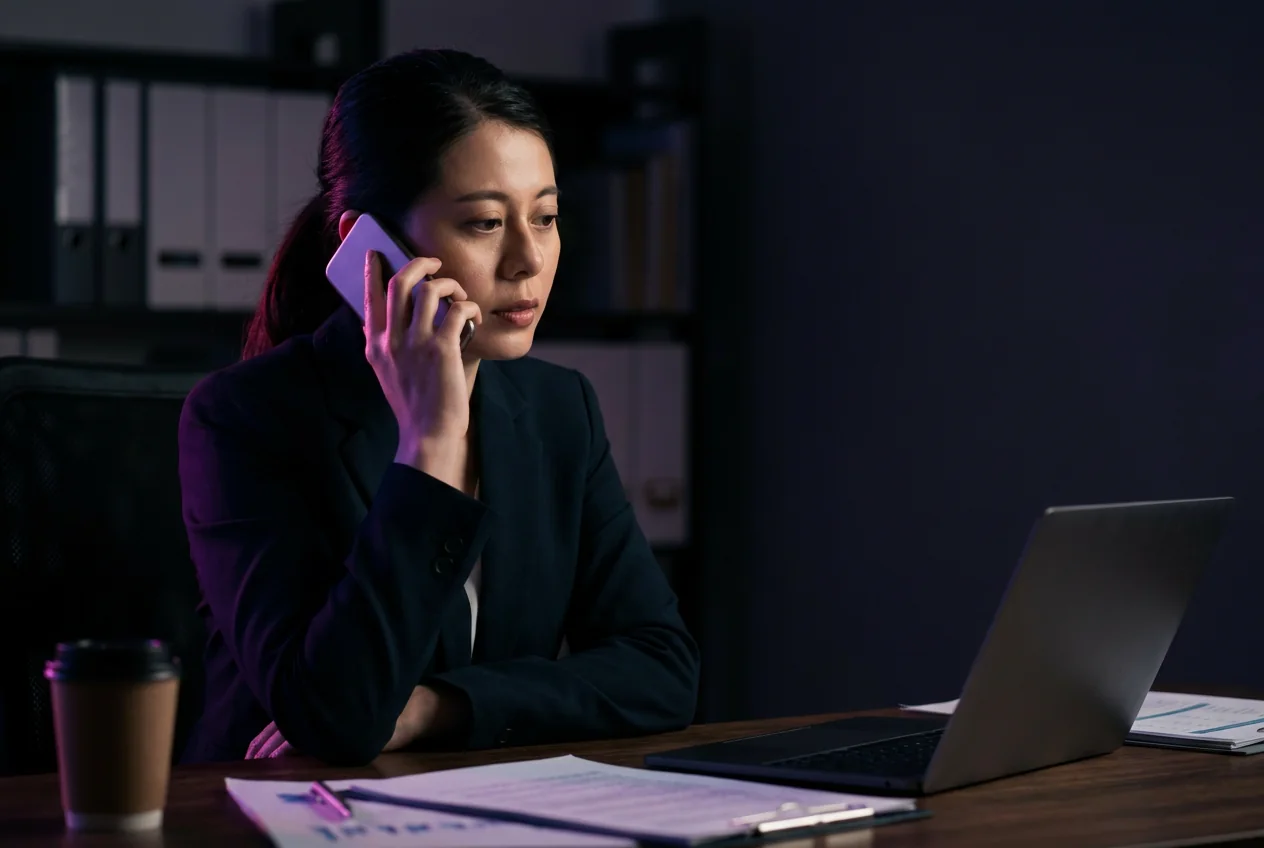Professionista al telefono nel proprio studio con documenti e computer sulla scrivania